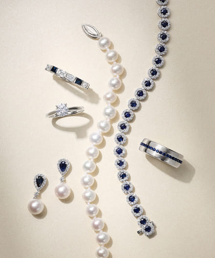 a diamond ring, pearl earring and necklace, a bracelet and ring layered together